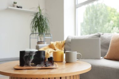 Oturma odasındaki masa üzerinde gerekli yağlarla hava nemlendirici, yakın plan.