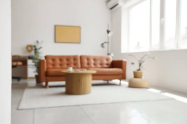 Rahat kahverengi kanepesi ve ahşap masası olan bulanık oturma odası manzarası.