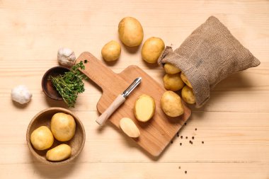 Tahta kesmek çiğ bebek patatesleri ve ahşap arka planda farklı baharatlar.
