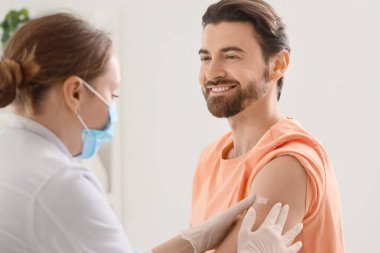 Klinikte aşıdan sonra doktor yaması uygulayan genç bir adam.