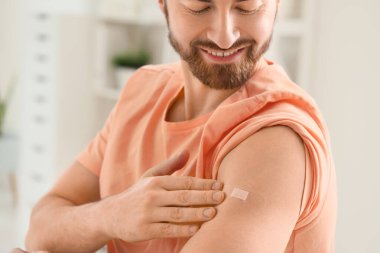 Klinikteki aşıdan sonra uygulamalı tıbbi yaması olan genç adam, yakın plan.