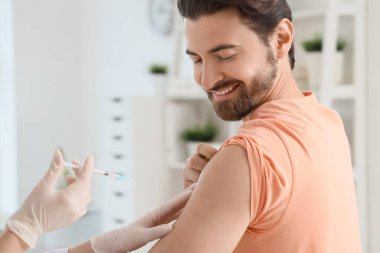 Genç adam klinikte aşı oluyor, yakın plan.