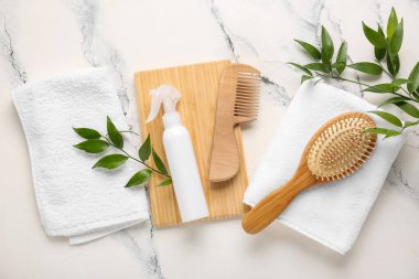 Arka planda saç spreyi, tarak, fırça ve temiz havlularla kompozisyon