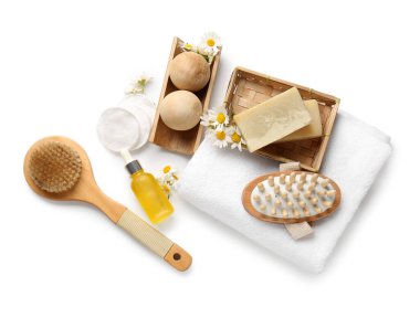 Papatya çiçekleri, sabun barları ve beyaz arka planda tahta masaj topları olan kompozisyon