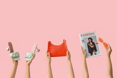 Pembe arka planda ayakkabı, güneş gözlüğü ve dergi taşıyan kadın el çantası.