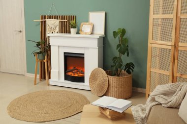 Oturma odasında turkuaz duvarın yanında kanepesi, dolabı ve sehpası olan bir şömine.