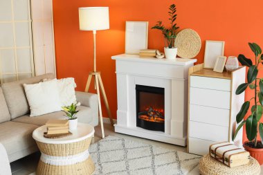 Kanepesi, tuvaleti ve turuncu duvarın yanında parlayan lambası olan bir şömine.