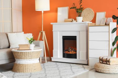 Kanepesi, tuvaleti ve turuncu duvarın yanında parlayan lambası olan bir şömine.