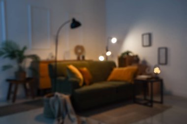 Bulanık oturma odası, yeşil kanepe ve akşam lambaları.