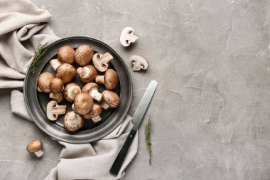 Gri grunge arka planda çiğ şampiyon mantarlı peçete ve tabak.