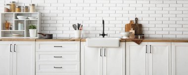 Mutfağın içinde beyaz tezgah, lavabo ve çatal bıçak var.