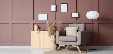 Şık koltuk, ahşap tuvalet ve oturma odasındaki kahverengi duvarın yanındaki lamba.