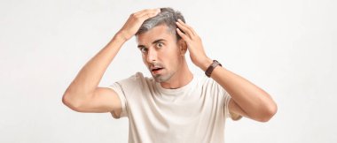 Açık arkaplanda gri saçlı stresli bir adam.