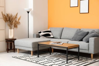 Güzel oturma odasının içinde rahat bir kanepe, halı, lamba ve kahve masası.