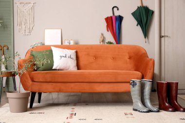 Kanepe, lastik bot ve şemsiyeli bir oda.