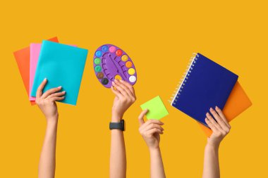 Palet, yapışkan notlar ve sarı arkaplan üzerine not defterleri olan birçok el