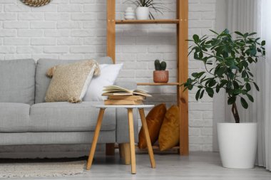 Ahşap raf ünitesi, kanepe ve oturma odasının iç tarafındaki beyaz tuğla duvarın yanındaki masa.