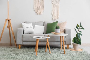 Gri kanepesi, kahve masası ve beyaz duvarın yanında standart lambası olan şık bir oturma odası.