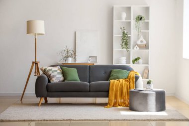 Oturma odasının içinde rahat bir kanepe, puf ve zemin lambası.