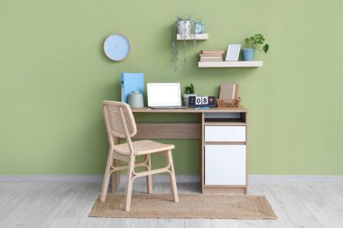 Modern dizüstü bilgisayarı, takvimi ve renkli duvara yakın kitapları olan şık bir iş yeri