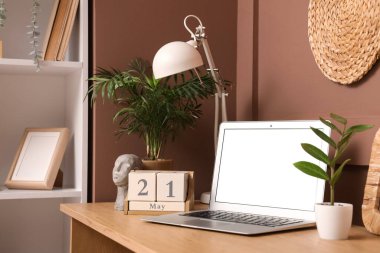 Modern dizüstü bilgisayar, küp takvimi 21 Mayıs, lamba ve ev bitkileri ahşap masa üzerinde