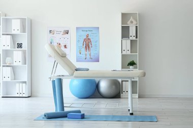 Koltuğu ve raf ünitesi olan fizyoterapistin ofisi.