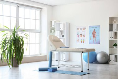 Koltuğu ve raf ünitesi olan fizyoterapistin ofisi.