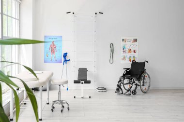 Koltuğu, spor malzemeleri ve tekerlekli sandalyesi olan bir fizyoterapist ofisi.