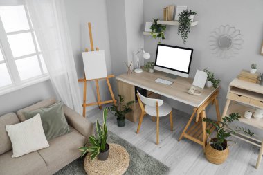 Interior of light office with workplace, sofa and green plants
