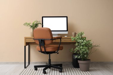 Ofiste boş bilgisayar monitörü ve bej duvarın yanında bitkileri olan işyeri