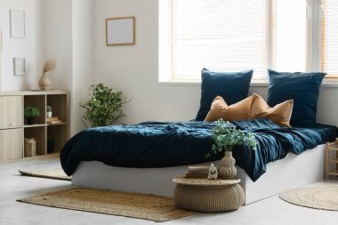 Rahat yataklı, siyah çarşaflı, puf ve çiçekli modern yatak odasının içi.