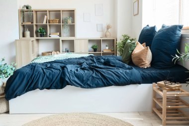 Rahat yataklı, siyah çarşaflı ve komodinli modern yatak odası.