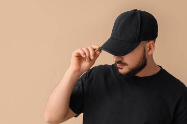 Bej arka planda şık şapkalı yakışıklı bir genç.