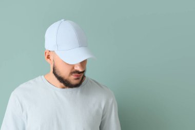 Mavi arka planda şık şapkalı yakışıklı bir genç.