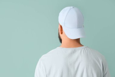 Mavi arka planda şık şapkalı yakışıklı bir genç.