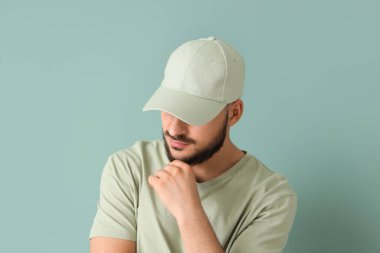 Mavi arka planda şık şapkalı yakışıklı bir genç.