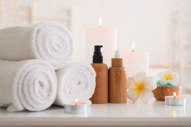 Temiz havlular, kozmetik ürünler ve yanan mumlar.