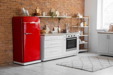 Mutfağın içinde retro buzdolabı, tezgah ve raf var.