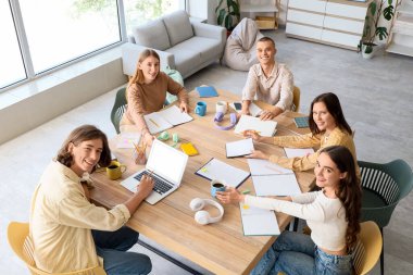 Sınıftaki bir grup öğrenci en üst düzeyde, masada ders çalışıyor.