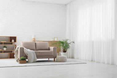 Işık perdesi, kanepesi ve raf ünitesi olan oturma odasının içinde.