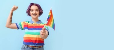 Açık mavi arkaplanda LGBT bayrağı olan genç bir kadın metin için yer var