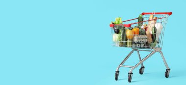 Mavi zemin üzerinde farklı taze ürünlerle dolu alışveriş arabası metin için yer var.