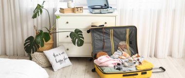 Otel odasında giysiler ve seyahat aksesuarlarıyla dolu bavulları boşalttım.