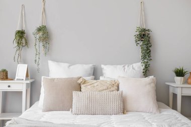 Cozy bed with soft pillows in interior of light bedroom