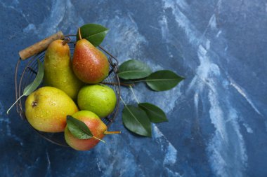 Mavi masada olgun armutlarla dolu sepet.