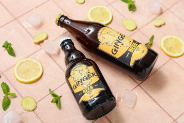 Bej arka planda taze zencefilli bira, nane, limon dilimleri ve buz küpleriyle kompozisyon, yakın plan.