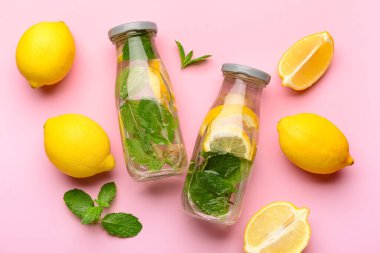 Pembe arka planda naneli lezzetli limonata şişeleri.
