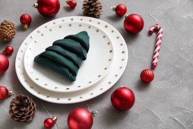 Gri grunge masa üzerinde katlanmış peçete ve Noel süslemeleri ile şenlik masası