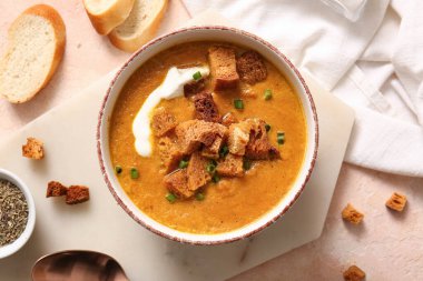 Bir kase kremalı çorba, kızarmış ekmek ve bej arka planda.