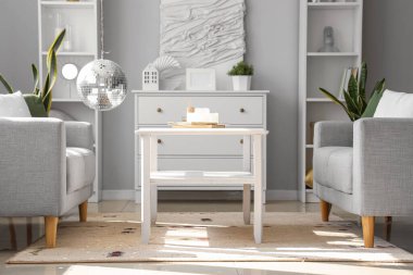 Modern oturma odasının içinde gri kanepeler, asılı disko topu ve kahve masası.